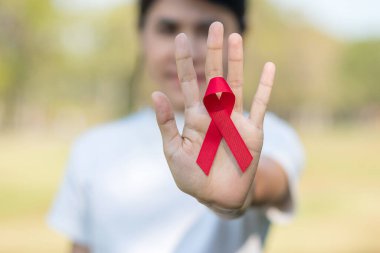Red Ribbon 'ın elini tutarak yaşayan ve hastalığa yakalananları destekliyorum. Sağlık ve güvenli seks konsepti. Aralık Dünya Yardım Günü ve çoklu miyelom kanseri farkındalığı ayı