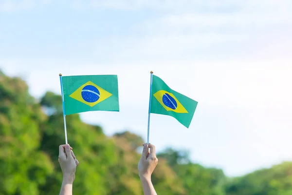 hand holding Brazil flag on blue sky background. September Independence day and Happy celebration concepts