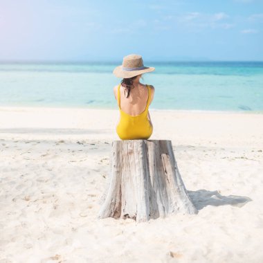 Sarı mayo ve şapkalı kadın turist, Tayland, Krabi 'deki Phi Phi Don Adası' ndaki bambu adasında tek başına deniz manzaralı güzel bir gezgin. hedef, yaz seyahati, tatil ve tatil konsepti