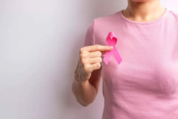 Pink October Breast Cancer Awareness month, woman hand hold pink Ribbon and wear shirt for support people life and illness. National cancer survivors month, Mother and World cancer day concept