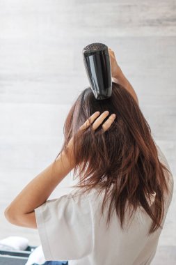 young woman using hair dryer at home or hotel. Hairstyles and lifestyle concepts
