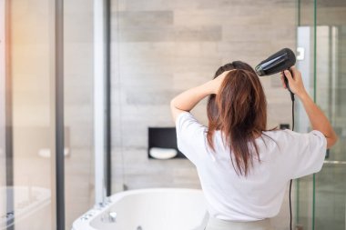 young woman using hair dryer at home or hotel. Hairstyles and lifestyle concepts