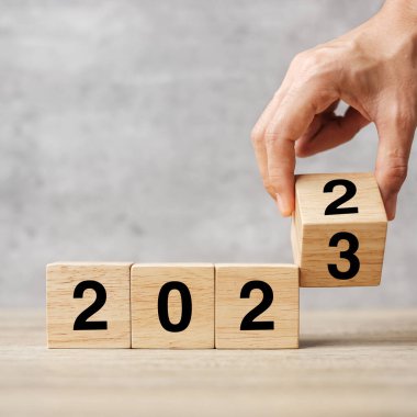 hand flipping block 2022 to 2023 text on table. Resolution, strategy, plan, goal, motivation, reboot, business and New Year holiday concepts