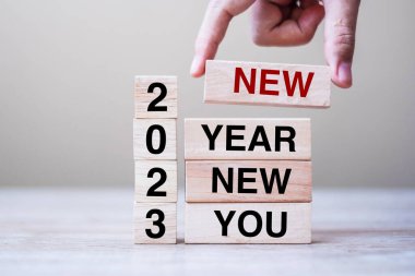 Yeni Yıl 2023 yazısıyla ahşap blokla el ele tutuşmak masa arkasında yeni bir sen. Çözüm, strateji, hedef, iş ve tatil kavramları