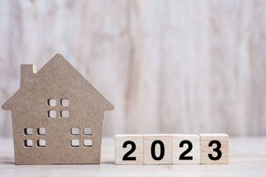 2023 Happy New Year with house model on table wooden background. Banking, real estate, investment, financial, savings and New Year Resolution concepts