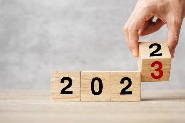 hand flipping block 2022 to 2023 text on table. Resolution, strategy, plan, goal, motivation, reboot, business and New Year holiday concepts