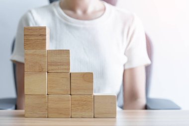 Bir kadın binanın üzerine ahşap blok yerleştiriyor. Liderlik, İş Süreci Planlama, Risk Yönetimi ve Stratejisi
