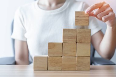 Bir kadın binanın üzerine ahşap blok yerleştiriyor. Liderlik, İş Süreci Planlama, Risk Yönetimi ve Stratejisi