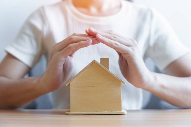 İş kadını el kaplaması ahşap ev modeli. gayrimenkul, konut sigortası, enflasyon, ekonomik durgunluk ve mülkiyet kavramları
