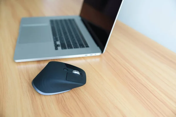 Ergonomic vertical mouse with laptop computer on adjustable desk at workplace, prevention wrist pain. De Quervain s tenosynovitis, Intersection Symptom, Carpal Tunnel or Office syndrome concept