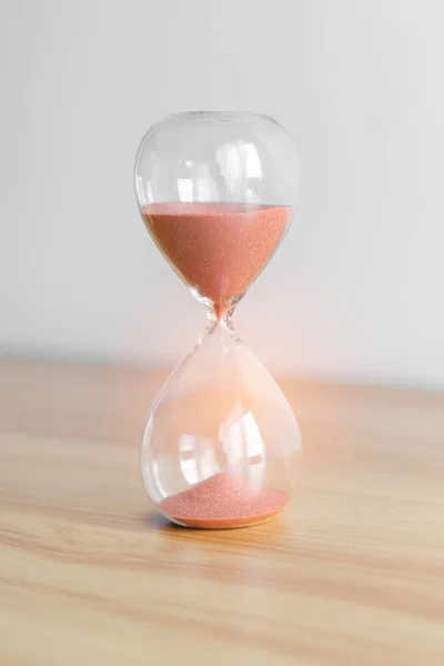 Hourglass on table, Sand flowing through the bulb of Sandglass measuring the passing time. countdown, patience, deadline, Life time and Retirement concept