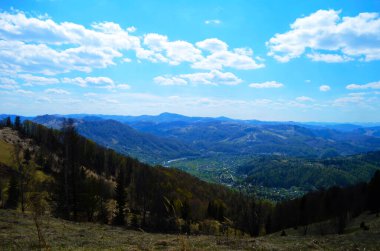 Gün batımında dağlarda kırsal manzara. Karpatların güzel manzarası. Akşam vakti çayırları ormanlık tepelerde yuvarlanıyor. İlkbaharda harika bir hava