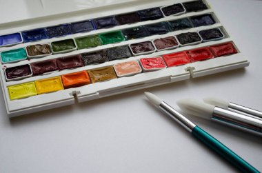 Birçok araç gereç sanatçılar fırçalar suluboya kutu boyaları beyaz izole arka plan