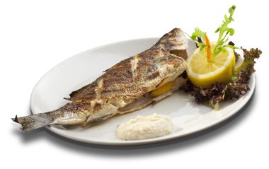 Beyaz çanak üzerinde Izgara Alabalık limon ile dekore edilmiştir.