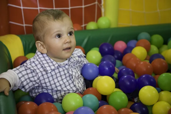 Toddler sitting in a basket of colored balls game — Stock Photo, Image