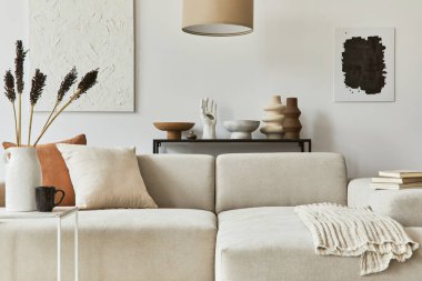 Poster çerçevesi ve yapı boyası, köşe kanepe, sehpa, tekstil ve kişisel aksesuarlarla dekore edilmiş rahat oturma odasının şık kompozisyonu. İskandinav klasiği.