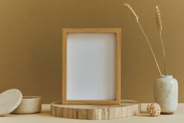 Poster çerçevesi, ahşap ve marbel gibi doğal malzemeler, kurumuş bitkiler ve kişisel aksesuarlarla donatılmış rahat yaratıcı iç mekan. Tarafsız ve sarı renkler, şablon.