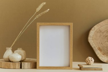 Poster çerçevesi, ahşap ve marbel gibi doğal malzemeler, kuru bitkiler ve kişisel aksesuarlarla süslenmiş rahat bir iç tasarımın kompozisyonu. Tarafsız ve sarı renkler, şablon.