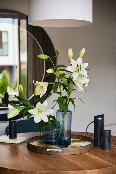 Elegant dining room interior with velvet armchair, design rouded wooden table and beautiful personal accessories. Glamour interior design inspiration. Details. Template