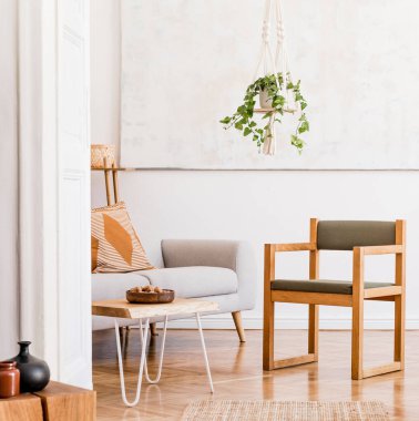 Gri kanepe, sandalye, sehpa, bitkiler, halı ve güzel aksesuarları olan yaratıcı, geniş bir daire kompozisyonu. Beyaz duvarlar ve parke zemin.