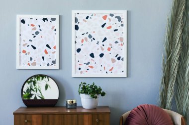 Şık oturma odası iç tasarımının yaratıcı kompozisyonu poster çerçeveleri, ahşap tuvalet, sandalye, yastık, bitkiler ve aksesuarlar. Modern İskandinav konsepti. Tarafsız duvarlar, parke zemin. Şablon.