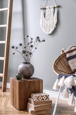 Yaratıcı ve rahat oturma odasının şık kompozisyonu Boho iç dekorasyonu ve rattan koltuğu. Gri duvarlar