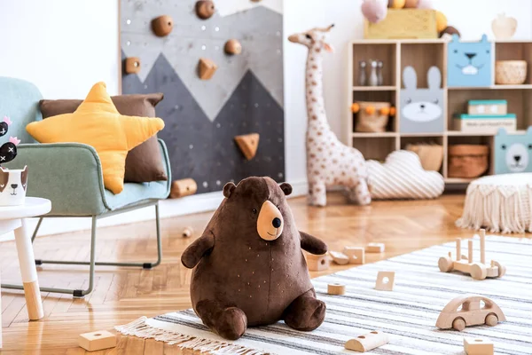 Modern scandinavian interior design of childroom with mint armchair, climbing wall for kids, design furnitures, soft toys, teddy bear and cute children\'s accessories. Stylish kidroom decor. Template.