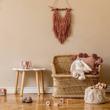 Doğal oyuncaklarla, asılı dekorasyonla, mobilyalarla, pelüş hayvanlarla, oyuncak ayılarla ve aksesuarlarla dolu şık bir çocuk odası. Bej duvarlar. Çocuk odasının iç tasarımı. Şablon.