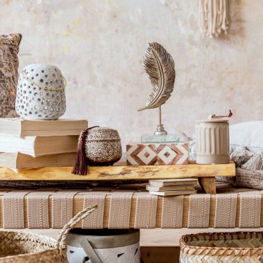 Tasarım bej şezlongu, güzel makrome, yastıklar, ahşap tepsi, kitap, dekorasyon ve ev dekorasyonunda zarif kişisel aksesuarları olan modern doğu oturma odası..  