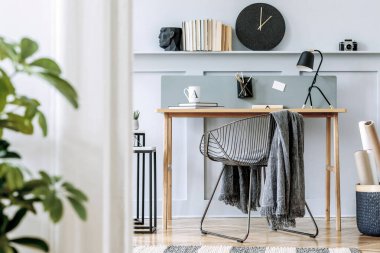 İskandinav ev içi ahşap masa, tasarım sandalyesi, ahşap panelli raf, bitki, masa lambası, halı, ofis malzemeleri ve modern ev dekorasyonunda zarif aksesuarlar..
