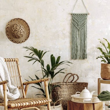 Oturma odasının iç kısmının şık ve çiçekli kompozisyonu içinde rattan koltuklar, tasarım kapları, dekorasyon, makrome ve şık ev dekorasyonu gibi pek çok tropikal bitki var..