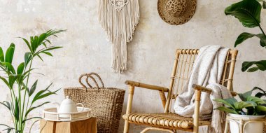 Oturma odasının iç kısmının şık ve çiçekli kompozisyonu içinde rattan koltuklar, tasarım kapları, dekorasyon, makrome ve şık ev dekorasyonu gibi pek çok tropikal bitki var..