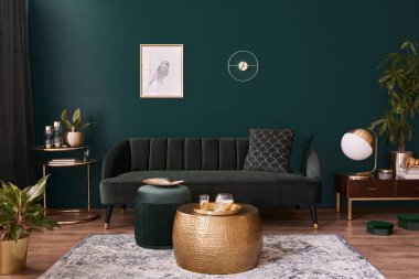 Modern iç tasarımı, yeşil kadife kanepesi, kahve masası, puf, altın süslemesi, bitki, lamba, halı, poster çerçevesi ve zarif aksesuarları olan lüks oturma odası. Şablon.