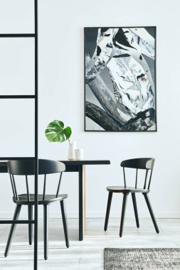 Ahşap aile masası, siyah sandalyeler, kahve fincanları, vazoda tropikal yaprak, duvarda soyut resimler ve zarif aksesuarlar. Modern ev dekorasyonu. Şablon. 