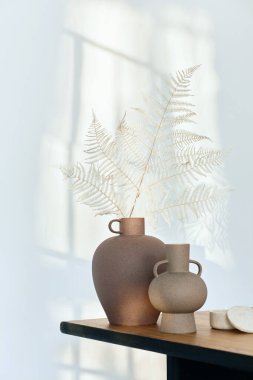 Ahşap masada, kurumuş çiçekli vazolarla süslü bir kompozisyon. Duvardaki güzel gölgeler. Modern iç mekanda soyut bir kavram. Şablon.