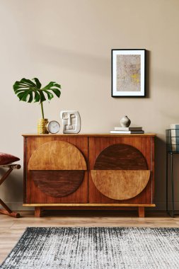 Tasarım ahşap klozet, tabure, vazoda tropikal yaprak, eşsiz dekorasyon, halı, poster çerçevesi ve zarif kişisel aksesuarlar. Klasik evdeki modern oturma odası.