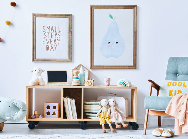 Cozy interior of child room with mint armchair, brown mock up poster frame, toys, teddy bear, dolls, plush animal, decoration. White wall. Warm kid space. Template.