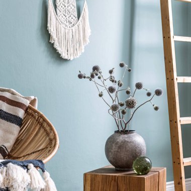 Oturma odasının içinde rattan koltuk, kurumuş çiçekli vazo tasarımı ve tahta küpün üzerinde cam bir top. Şablon. 