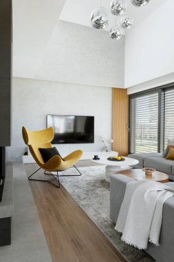 Köşedeki bej kanepe, sehpa, yerde halı ve minimalist aksesuarlarla oturma odasının şık kompozisyonu. Panoramik pencere. Şablon.