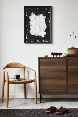Poster çerçevesi, kahverengi ahşap klozet, koltuk ve küçük ev dekorasyonlarıyla şık bir oturma odası kompozisyonu. Beyaz duvar. Uzayı kopyala Şablon.