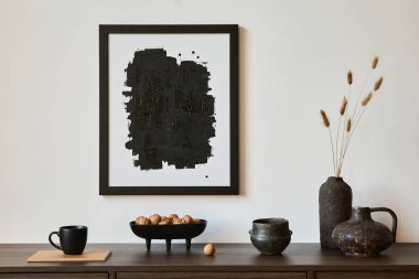 Modern oturma odası iç tasarımının yaratıcı kompozisyonu. Poster çerçevesi, kahverengi tuvalet, vazolar ve kişisel aksesuarlar. Beyaz duvar. Uzayı kopyala Şablon