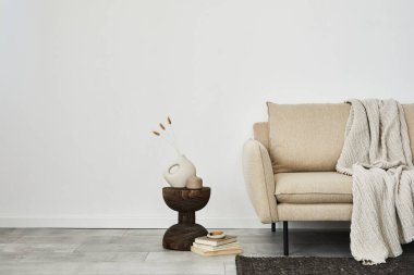 Creative composition of elegant minimalisit living room interior. Beige modern sofa, dar wooden side table and stylish personal accessories. Wallpaper. Copy space. Template.  