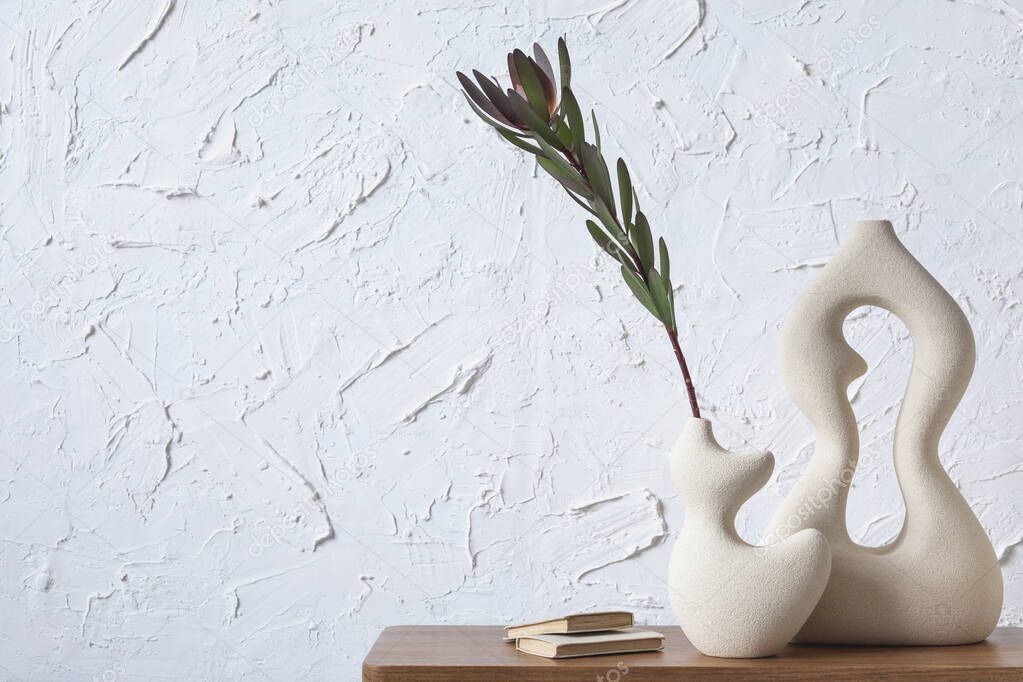 Creative minimalistic composition of home interior with handmade clay vases, sidetable and elegant personal accessories. Copy space. Wall paper. Template