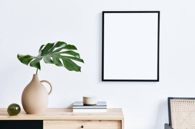 Poster çerçevesi, ahşap klozet, kitap, seramik vazoda tropikal yaprak ve zarif kişisel aksesuarları olan şık bir oturma odası. Minimalist ev dekorasyonu konsepti. Şablon.