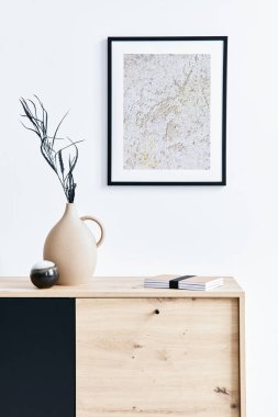 Poster çerçevesi, ahşap klozet, kitap, seramik vazoda yaprak ve zarif kişisel aksesuarları olan şık bir oturma odası. Minimalist ev dekorasyonu konsepti. Şablon.