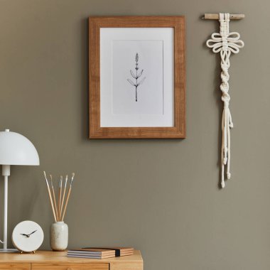 Ahşap masa, rattan koltuk, kahverengi model poster çerçeve, makrome, ofis malzemeleri, lamba, dekorasyon ve ev dekorasyonunda zarif kişisel aksesuarları olan ev içi bohem iç mekan.. 