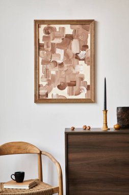 Poster çerçevesi, kahverengi ahşap klozet, koltuk ve küçük ev dekorasyonlarıyla şık bir oturma odası kompozisyonu. Beyaz duvar. Uzayı kopyala Şablon.