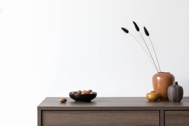 Beyaz duvarlı yaratıcı minimalist kompozisyon ve ahşap komodindeki küçük kişisel aksesuarlar ve vazolar. Uzayı kopyala Şablon.