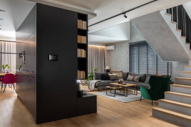 Köşedeki gri kanepe, yeşil kadife koltuk, sehpa, ahşap zemin, tasarım mobilyaları ve minimalist kişisel aksesuarlarla oturma odasının şık kompozisyonu. Modern ev dekorasyonu. Şablon.