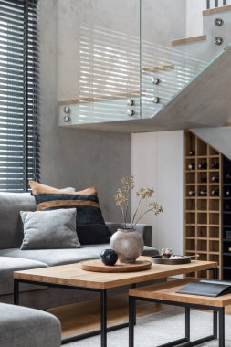 Köşedeki gri kanepe, yeşil kadife koltuk, sehpa, ahşap zemin, tasarım mobilyaları ve minimalist kişisel aksesuarlarla oturma odasının şık kompozisyonu. Modern ev dekorasyonu. Şablon.